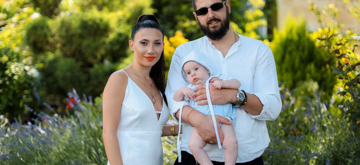 Charming family portrait of parents with a baby in a vibrant summer garden setting.