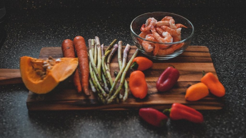 a wooden cutting board topped with carrots and asparagus