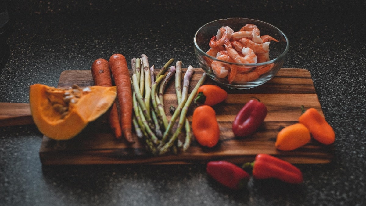 a wooden cutting board topped with carrots and asparagus